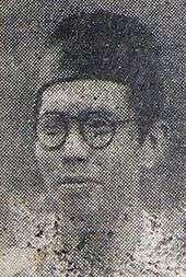 A man in spectacles and a songkok, looking left