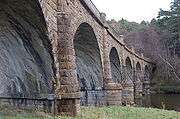 Close-up of a land-based pier with the soffit of one of the arches in the foreground. In the background other arches span the river as the viaduct curves gently to the right