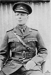 An informal portrait of a man in military uniform sitting down with his head cocked slightly to the side.