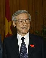 a smiling man with greying black hair, wearing a suit and tie