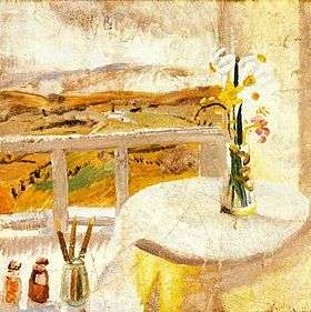 A landscape, mostly yellow, a white sky above; in the foreground a white railing and a white-covered table with a vase of yellow flowers