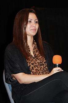 A woman with black hair is seated at a table.