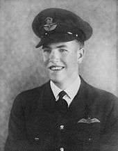 Studio portrait of young man wearing dark military uniform with pilot's wings and peaked cap