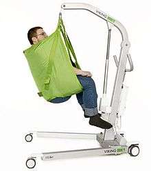 A patient sits in a sling lift with an aluminium frame