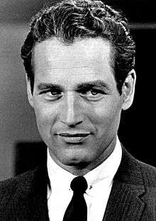 Black and white headshot of a man wearing a coat, shirt, and tie