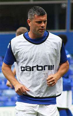 Grey-haired man wearing blue and white sports clothing