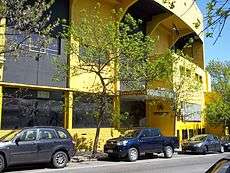 Yellow, multi-story building with cars parked in front