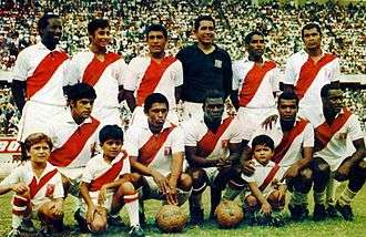 Photo of eleven men, six standing and five crouching, inside a stadium