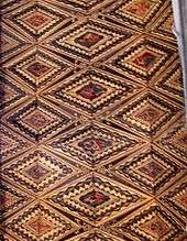 This wooden ceiling is painted in red, yellow and brown with figurative motifs framed in diamond shapes