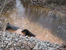 A dirty brown creek with garbage in it