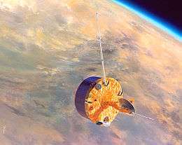 A stubby barrel-shaped spacecraft in orbit above Venus. A small dish antenna is at the centre of one of its end faces