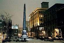 Obelisk and four-story building on winter evening