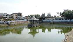 image of a temple tank with temple tower and complex in the background