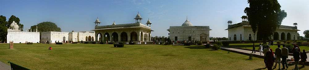 Many white buildings, with large grassy area in foreground