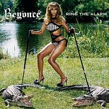 A brunette woman is standing near a swamp. She wears a two-piece bikini with black-and-white squares as its pattern. With her hands, she grabs straps that hold crocodiles. In the center, the word "Beyoncé" and "Ring the Alarm" are written in a white font.