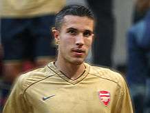 Head and shoulders of a man with short black hair wearing a golden football jersey.