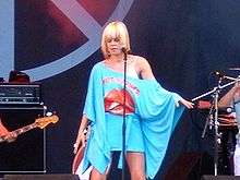 Blonde singer in oversized blue top onstage