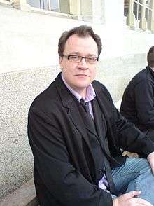 Davies sitting with his back towards a marble-effect wall.