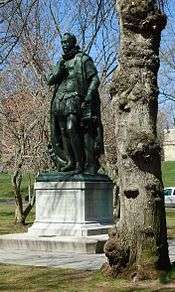 Bronze statue of a man in Elizabethean-period dress on a stone base