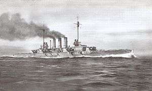 A large gray warship steams at full speed; thick black smoke pours from its three smoke stacks.