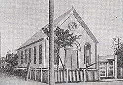 A black-and-white drawing of an old wooden church. The church is small and has no steeple.