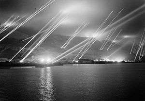 The Rock of Gibraltar, seen from the west, with at least 23 searchlights sending beams of light up into the night sky