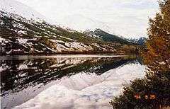 A view across Summit Lake from a point on the Summit Lodge turnoff with snow patches on the mountains behind