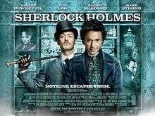 Robert Downey, Jr. and Jude Law, in-character. The background is a window display, featuring shelves containing miscellaneous objects relating to the story. The poster reads "Sherlock Holmes" across the top, with the tagline "Holmes for the holiday" centered at the bottom. The poster is predominately turquoise coloured.