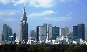 Mid-level view of a city; the tops of trees in the foreground with many high-rise buildings in the background