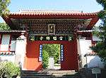 Small wooden gate painted in red, green and blue. Boards with Chinese characters are attached to the gate.