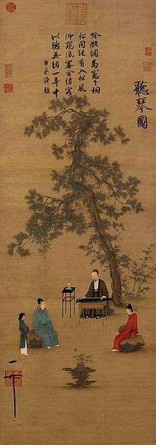 A long, vertically aligned painting of a several people listening to music under the shade of a tree. At the center of the painting, about a third of the way up from the bottom, a man in a green robe sits playing a stringed instrument that is built into a desk shaped container. To his left and right, further towards the bottom of the page, sit two men in robes, one on each side, listening to the music. A woman is standing behind the man on the left. The entire top half of the painting is dominated by a thin, angular tree, and a block of text above it.