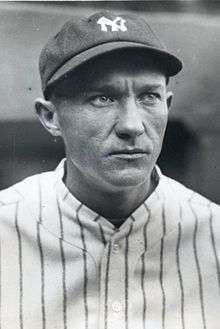 A close-up of a man wearing a baseball cap with an "NY" on the front and a pin-striped jersey looks to the right.