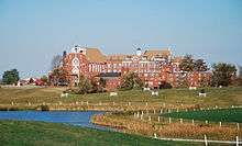 A multi-story red brick chapel with a stream in front of it