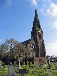 The west end, with a rose window, and the steeple of a Gothic style church, with a clock face; gravestones in the foreground and a leafless tree to the left