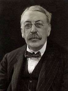 head and shoulders shot of an elderly man with full head of hair, moustache and pince-nez