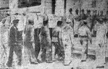 A line of men carrying a casket