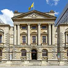 A stone building facade with a classical pediment and Ionic columns