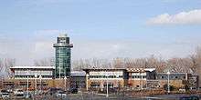 Across a parking lot is a two-story building with a circular tower that is offset from the center of the building.