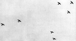 A distant photo taken from ground where several bombers are flying in the air.