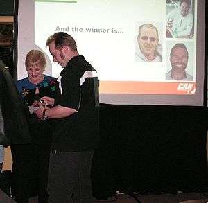 2007 awards ceremony, with award winner Tama Easton and Transport Minister Annette King standing in front of a screen showing one of the slides; somebody else walking through the photo