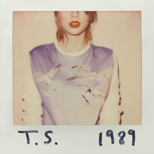 A polaroid of Swift with shoulder-length blonde hair wearing red lipstick and a long-sleeved sweater with a picture of birds in the sky. Her face is cut off by the frame above the nose and "T. S." and "1989" are written on the white polaroid frame with black marker.