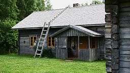 Rustic one-story wooden house with ladders to (and across) the roof