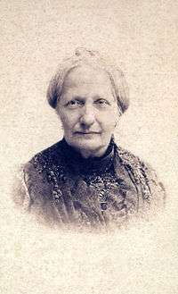 Head and shoulders sepia photograph showing an older woman with gray hair and wearing a dark lace dress