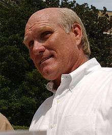 A balding man, who is wearing a white shirt.