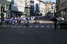 A police officer on a motorcycle leads runners of all ages down a city street