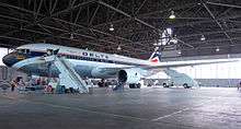 Side view of a parked Delta Air Lines twin-engine jet in hangar, with stairs mounted next to the aircraft's forward door.