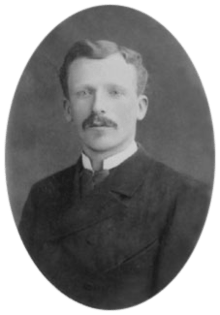 Headshot photo of a young man, similar in appearance to his brother, but neat, well-groomed and calm.