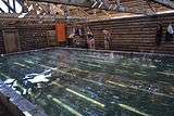 Interior of a wooden structure containing a spa pool, with people