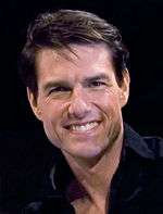 Head and upper body of a man with short brown hair, wearing a black shirt, smiling.