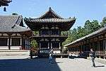 Wooden building with white walls and a veranda with balustrade on the upper floor.